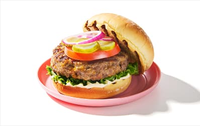 Open-face burger, dressed with mayo, lettuce, tomato, pickle and red onion. 
