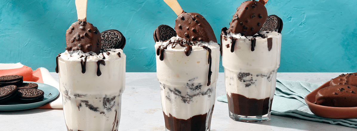Three Cookies and Cream Ice Cream Floats topped with Cookies & Cream ice cream bars, an Oreo and chocolate syrup
