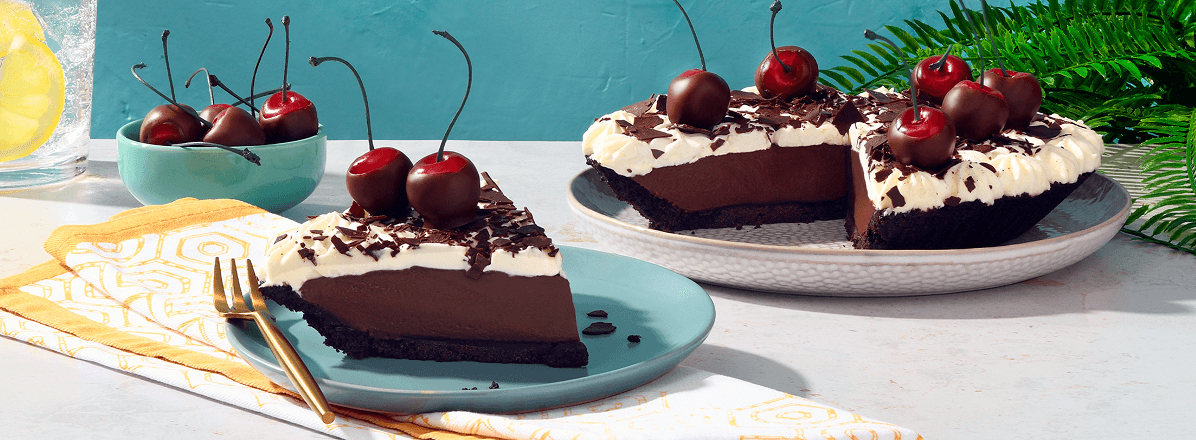 Chocolate cream pie topped with fresh chocolate dipped cherries with one slice taken out of it.