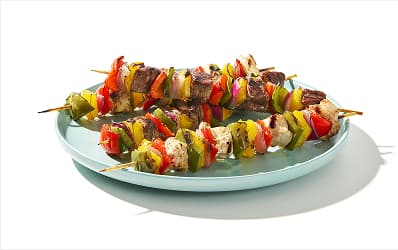 Variety of grilled kebabs, including  chicken, beef and pork skewered with bell peppers and red onion.  
