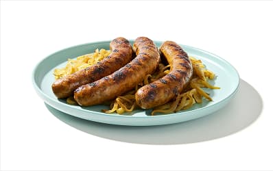 Three sausages on a bed of sautéed onions.
