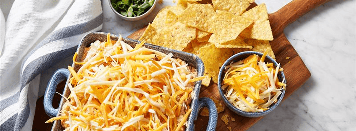 <p>square baking pan layered with dip, topped with shredded chicken and cheese</p>
