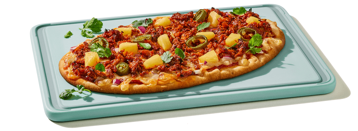 Al pastor flatbread on turquoise cutting board