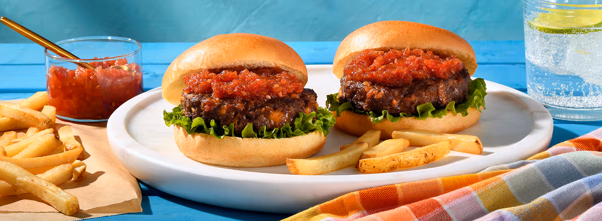 Cheddar & Bacon medium chuck burgers topped with tomato relish with fries off to the side