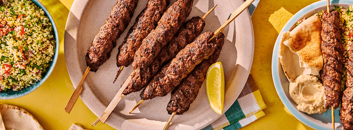 Beef kefta skewers on a plate with a tabbouleh salad to the side