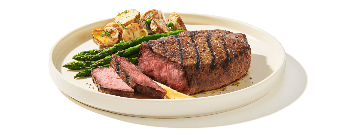 Sirloin Tri Tip Grilling steak on a plate with side of grilled asparagus and mushrooms to the side