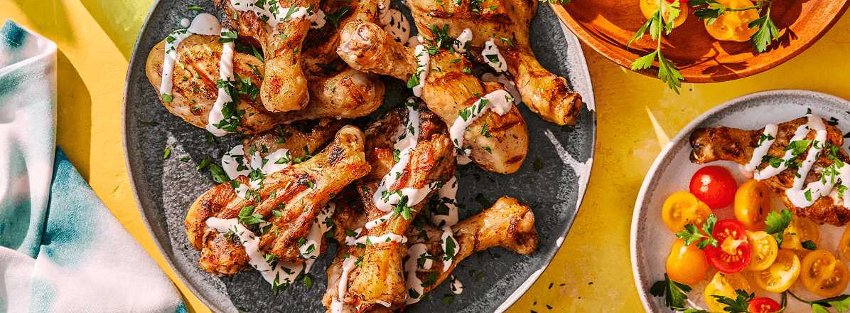 Overhead shot of grilled butterfly chicken drumsticks with a light drizzle of Caesar marinade and topped with fresh parsley