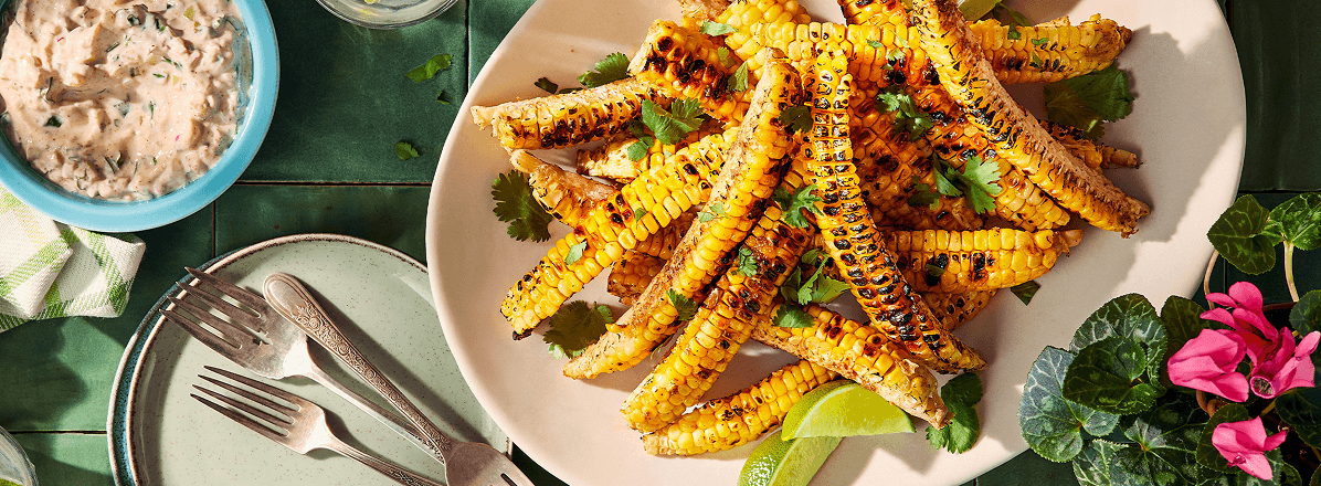 Overhead shot of corn ribs on a white plate, corn ribs have been charred and topped with spices, and cilantro