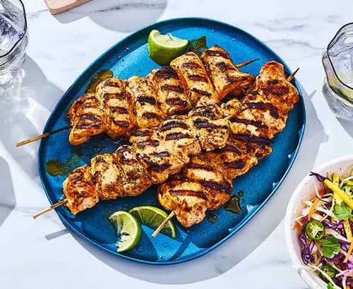spicy grilled chicken kabobs on blue platter