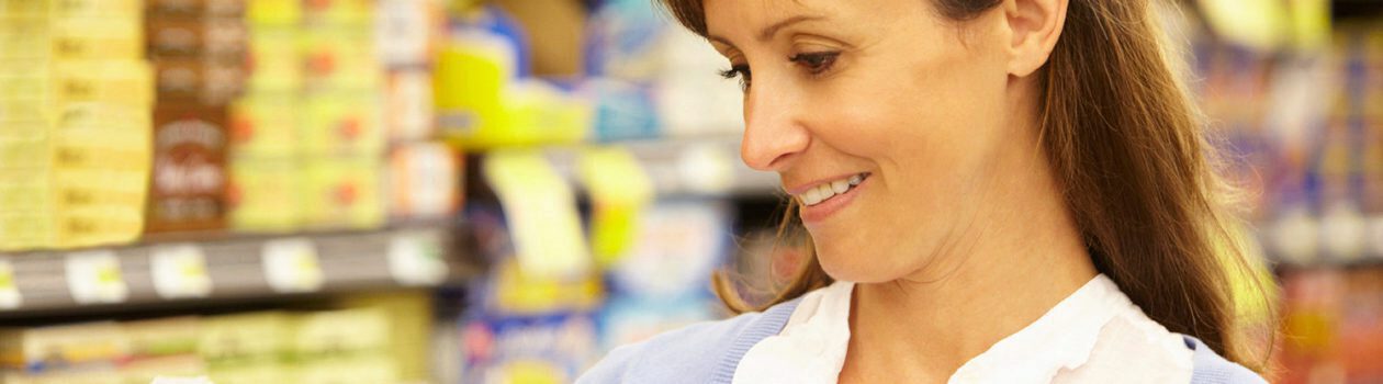 Woman reading food nutrition labels inside of grocery store