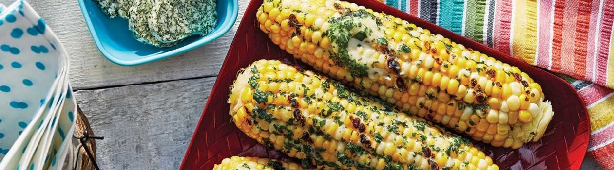 Garlic-Herb Butter over corn on the cobs on a set picnic table