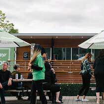 people sitting and standing around tables in front of the Sobeys food truck