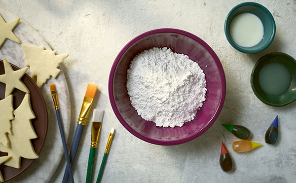 ingredients to make royal icing - icing sugar, lemon, milk and food colouring - on a table