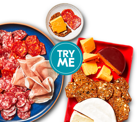 charcuterie One platter of cheese and crackers with fruit, and the other holds thin slices of cured meats.