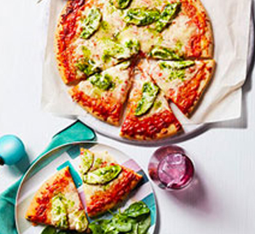 Pesto pizza sliced and on marble plate.