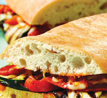 Ciabatta bun stuffed with grilled veggies and sliced in half.