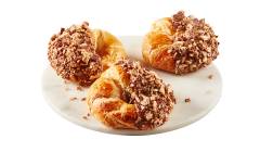 croissants-coffee-crisps Close up of croissant half dipped in Coffee Crisp spread that’s coated in candy bar crumbs on white plate.