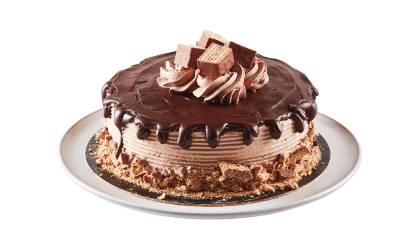 dessert_cake_coffee_crisp Layered cake iced with a fudge topped pour-over effect, finished with candy bar pieces on a white plate.
