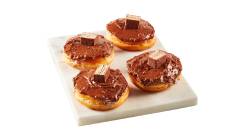 donuts-coffee-crisp Four donuts spread and filled with Coffee Crisp chunks and spread, presented on square white marble surface.