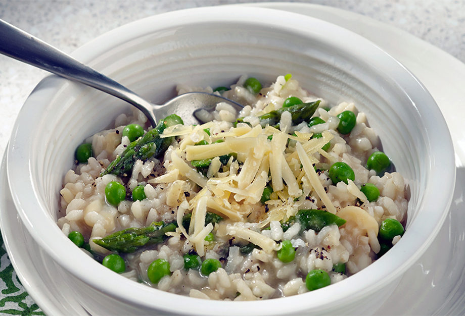 Bowl of asparagus, pea and gouda risotto with a spoon in bowl.