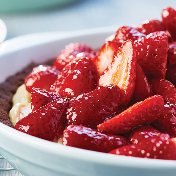 Mounds of glazed sliced strawberries over a cream cheese filling and chocolate chip crust in a white pie plate.