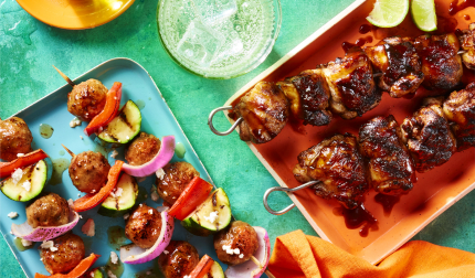 Kabobs-From-Around-TheWorld Four blue and orange hued platters loaded with kabobs from around the world on a blue background.