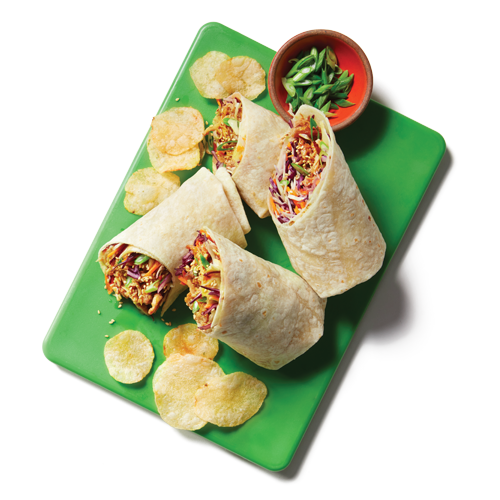  Four pieces of a wrap style sandwich filled with Korean-style marinated pulled pork, coleslaw, green onions and sesame seeds sitting atop a green cutting board.