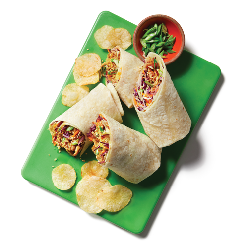 Four pieces of a wrap style sandwich filled with Korean-style marinated pulled pork, coleslaw, green onions and sesame seeds sitting atop a green cutting board.