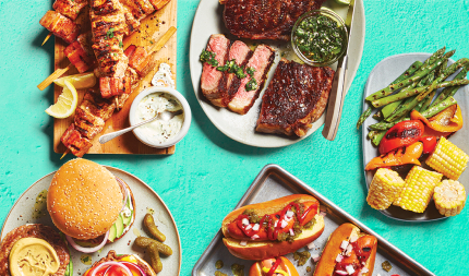 Last-summer's-grilling-image A variety of grilled meats including burgers and hot dogs on a blue background.