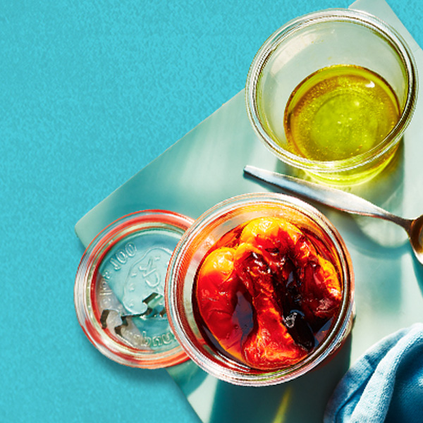 Glass jars filled with roasted red peppers and oil. 