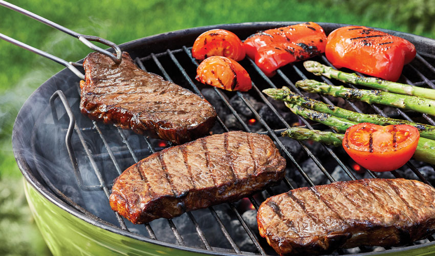 Steaks-and-veg-on-grill Steaks and vegetables on a green, charcoal grill.