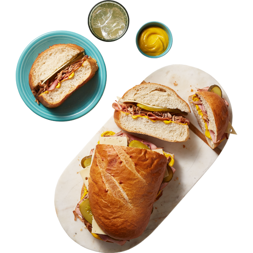 A deli department meat and cheese-stuffed dagwood sandwich served on a French loaf with shredded lettuce and tomato slices.