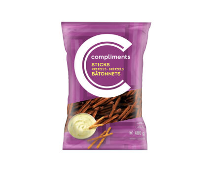 Purple bag of Compliments Pretzel Sticks with a peek a boo window, and an image of a dip with some sticks beside it. 
