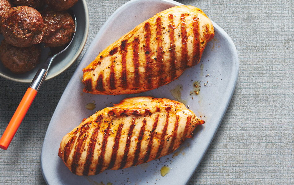 Grilled marinated boneless skinless chicken breast sitting on a blue plate.