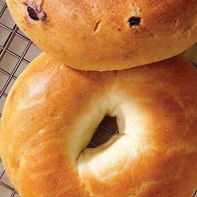 Various New York–style bagels on a wire rack over a white countertop.