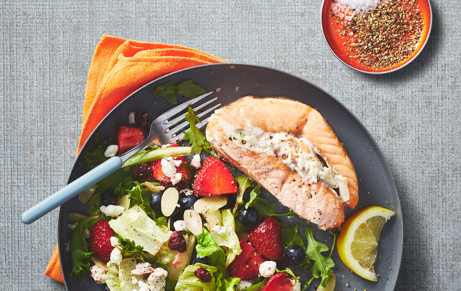 Individual salmon roast on a gray plate with a side of salad.