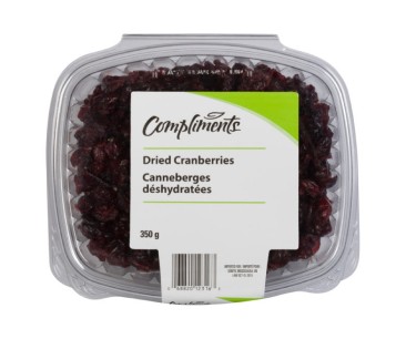 Clear tub of dried cranberries with white and green Compliments label.
