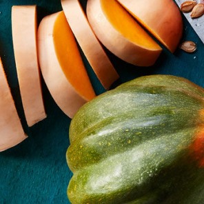 Variety of squashes sliced and on a green cutting board next to a knife.
