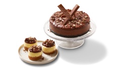 cheesecakes Three mini cheesecakes topped with KitKat spread and pieces sitting on a white plate. 6 inch chocolate cheesecake topped with KitKat spread and bar pieces.