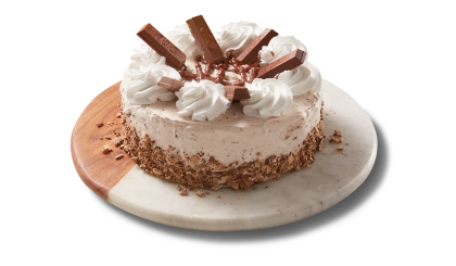 full_triple_layer_cake Chocolate triple layer cake covered in icing and Kit Kat crumbs on the side, topped with chocolate icing, and pieces of the candy bar.