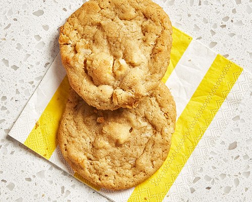 Two piña colada cookies sitting atop a yellow and white–striped paper napkin.