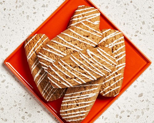 Six rectangular-shaped root beer cookies sitting on a red plate. 