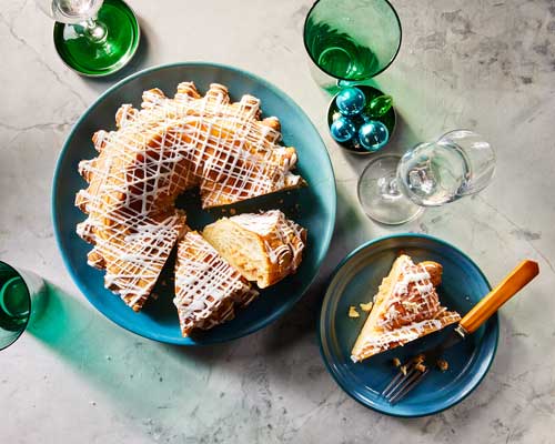 Almond Kringle cake on a blue plate sitting atop a gray marble counter top.