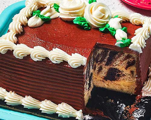 Vanilla and chocolate marble slab cake with a corner piece cut out of it sitting on a blue platter.