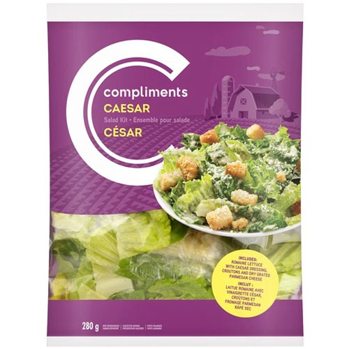 Purple bag of Compliments romaine lettuce with illustration of a barn and photo of composed Caesar and/or bottle of white Caesar dressing with black bottle top and Comps Plant Based logo