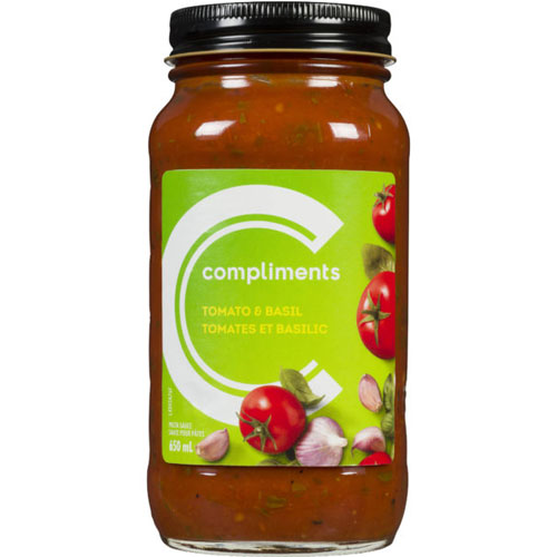 Glass jar of Compliments Tomato & Basil Pasta Sauce with a green label featuring fresh tomatoes, garlic and basil leaves