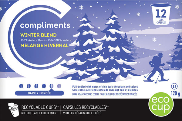 Blue and white illustration on box of Compliments Winter Blend Coffee Cups depicting a man cross country skiing in a snow-topped tree lined wonderland.