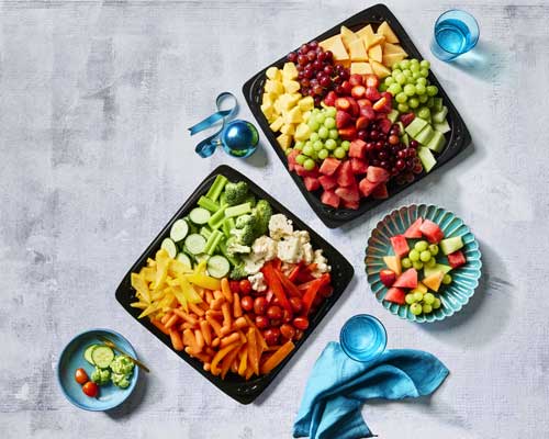 Entertaining trays full of assorted fruit or veggies on a black, portable container.