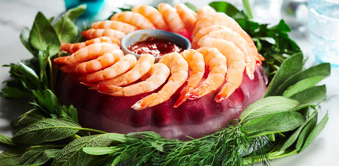 A cranberry studded ice ring topped with a shrimp ring and framed by fresh herbs. 