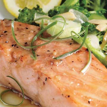 Close-up of an orange glazed salmon filet next to a side of steamed broccoli.